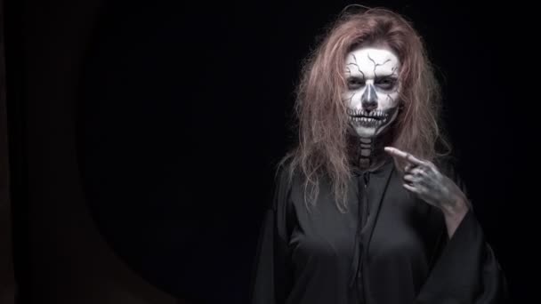 Concept, mooie make-up voor Halloween. Portret van een jong sexy meisje met schedel make-up. op een zwarte achtergrond, gezicht in het donker. Close-up — Stockvideo