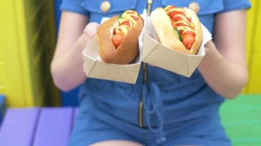 kız elinde bir yaz gününde sokakta iki lezzetli sosisli tutar