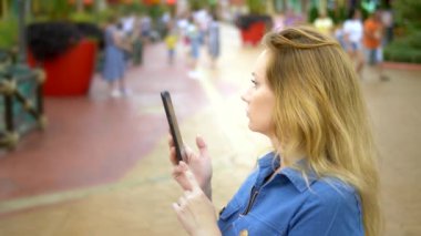 Bir kadın bir akıllı telefonda bir harita uygulaması kullanır bir yaya sokakta ayakta iken.