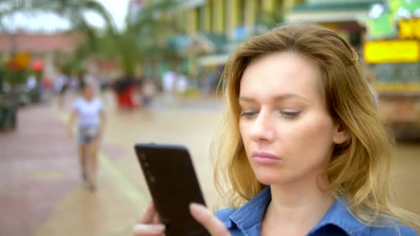 La cara de una joven atractiva usa el teléfono en el centro de la ciudad. en un día soleado de verano. primer plano  . — Vídeo de stock