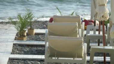 Bulanık arka plan. Sahilde plaj sandalyeleri ve şemsiyeler, tanınmayan insanlar istirahat