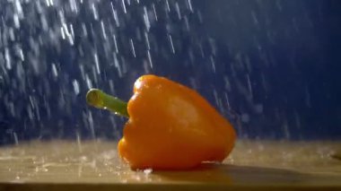 Yağmur jetleri altında stüdyoda karanlık bir arka planda tatlı portakal biber.