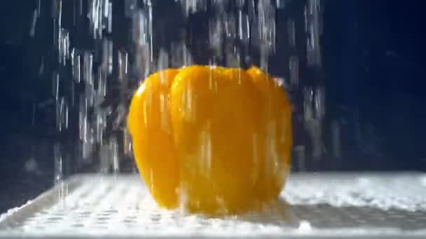 Söt gul peppar på en mörk bakgrund i studion under jets av regn. — Stockvideo