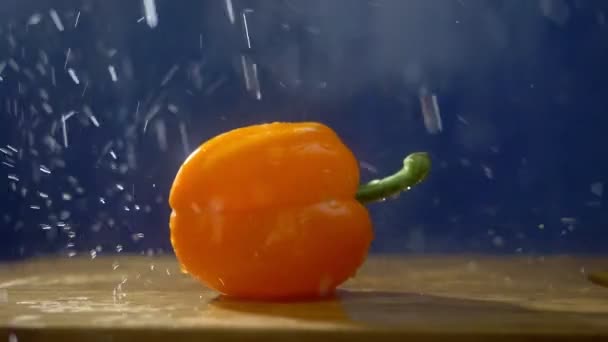 Zoete sinaasappel peper op een donkere achtergrond in de studio onder straal van regen. — Stockvideo