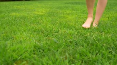 kadın bacaklar çiğ yalınayak yeşil çim üzerinde yürümek. Close