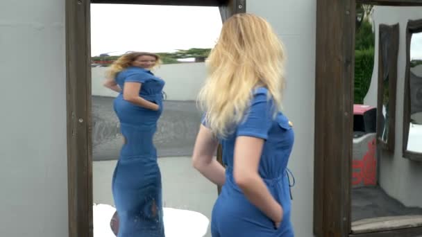 Crooked mirrors. young slim woman looks in a crooked mirror with a smile. — Stock Video