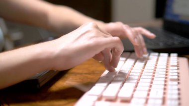 The concept of multitasking or cheating in social networks. One woman types simultaneously on three keyboards. hand closeup. clipart