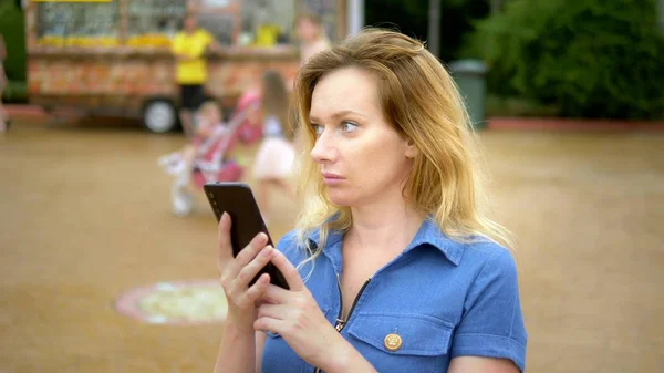 Das Gesicht einer jungen attraktiven Frau benutzt das Telefon in der Innenstadt. an einem sonnigen Sommertag. Nahaufnahme . — Stockfoto