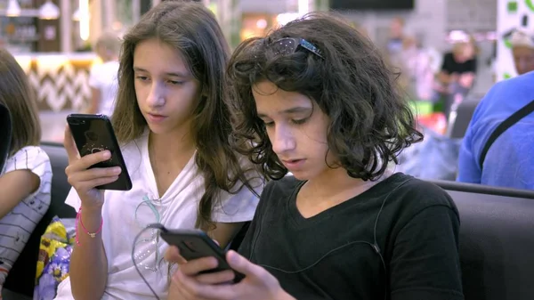 As crianças na área de espera do aeroporto usam um smartphone. conceito de viagem — Fotografia de Stock