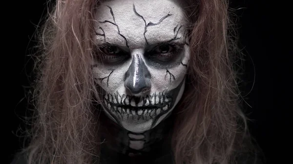 Concept, beautiful makeup for halloween. Portrait of a young sexy girl with skull makeup. on a black background, face in the dark. close-up — Stock Photo, Image