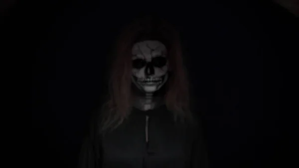 Concetto, bel trucco per Halloween. Ritratto di una giovane ragazza sexy con trucco del cranio. su uno sfondo nero, faccia al buio. primo piano — Foto Stock
