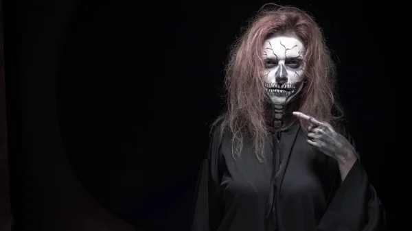 Concept, beautiful makeup for halloween. Portrait of a young sexy girl with skull makeup. on a black background, face in the dark. close-up — Stock Photo, Image