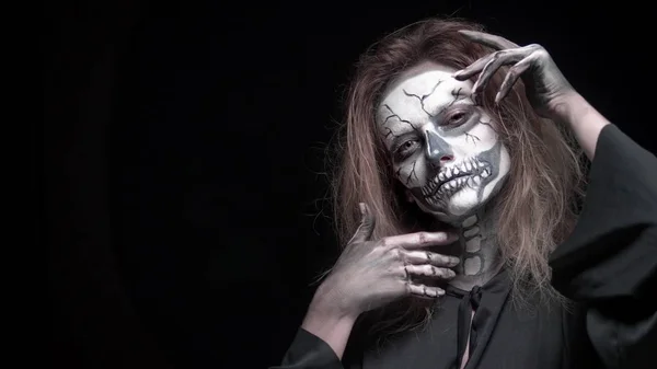 Concept, beautiful makeup for halloween. Portrait of a young sexy girl with skull makeup. on a black background, face in the dark. close-up — Stock Photo, Image