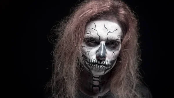 Concepto, hermoso maquillaje para Halloween. Retrato de una chica sexy joven con maquillaje de cráneo. sobre un fondo negro, cara en la oscuridad. primer plano —  Fotos de Stock