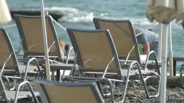 Fondo borroso. sillas de playa y sombrillas en la playa, personas irreconocibles descansando — Vídeo de stock