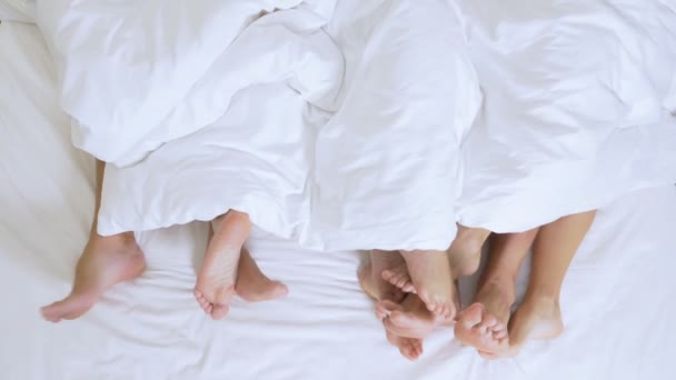 Concepto Clubes sexuales, clubes swing, clubes de estilo de vida, grupos formales e informales. pies de un grupo de personas bajo una manta blanca en una sábana blanca en una cama king size — Vídeos de Stock