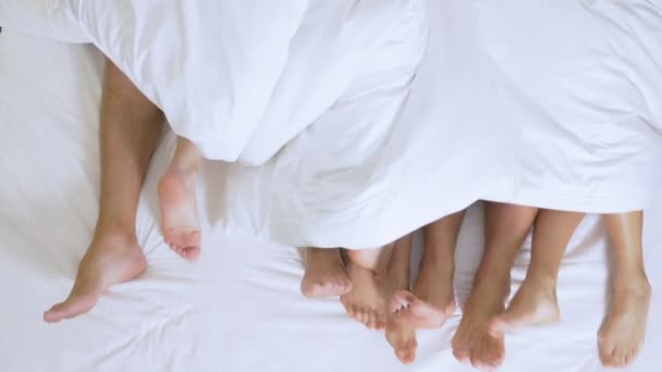 Concetto Sex club, swing club, lifestyle club, formali, gruppi informali. piedi di un gruppo di persone sotto una coperta bianca su un foglio bianco su un letto king size — Video Stock