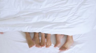 Konsept Seks kulüpleri, salıncak kulüpleri, yaşam tarzı kulüpleri, resmi, gayri resmi gruplar. bir kral yatak üzerinde beyaz bir levha üzerinde beyaz bir battaniye altında insanların bir grup ayak