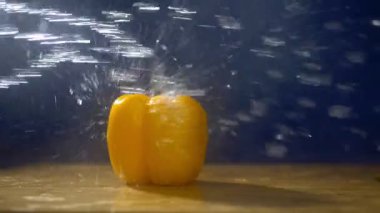 Yağmur jetleri altında stüdyoda karanlık bir arka planda tatlı sarı biber.