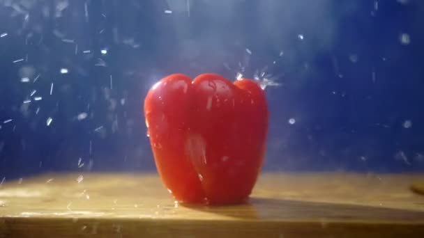 Γλυκό κόκκινο πιπέρι σε ένα σκοτεινό φόντο στο στούντιο κάτω από πίδακες βροχής. — Αρχείο Βίντεο