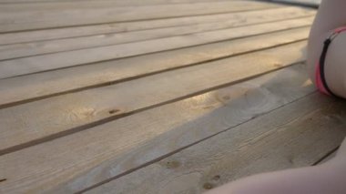 parlak pembe mayo muhteşem göğüsleri ile güzel ince kadın yatıyor ve deniz üzerinde ahşap bir terasta güneşlendi.