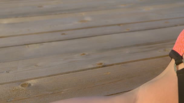 Bella donna magra con seni splendidi in un costume da bagno rosa brillante si trova e prende il sole su una terrazza in legno sopra il mare . — Video Stock