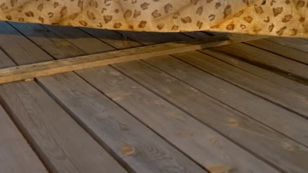 Een mooie slanke vrouw met prachtige borsten in een geel badpak ligt en zonaanbakt op een Luipaard bed, dat staat op een houten terras boven de zee. — Stockvideo