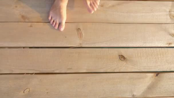 Primo piano. piedi nudi maschili camminano su tavole di legno . — Video Stock