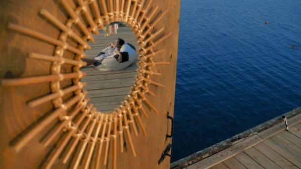 Una puerta al mirador en el muelle sobre el mar, con un espejo decorativo y el mar y el cielo reflejados en él . — Vídeo de stock