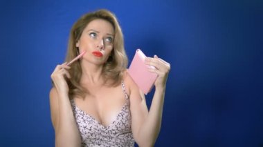 Pembe defterli ve kalemli pinup kızı. not defterine ne yazılması gerektiğini düşünür. Retro tarzı . Romantizm aşk, olumlu duygular. mavi arka plan, kopyalama alanı