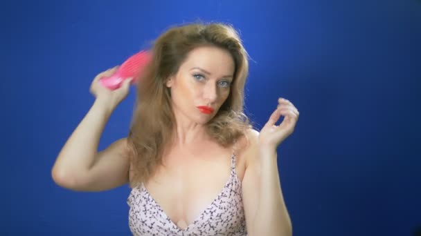 Концепція дівочої пін-ап. Жінка випрямляє волосся, дивлячись на камеру, блакитний фон. копіювання простору — стокове відео