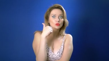 Büyüleyici kız konsepti. mavi arka plan Kopyalama alanı. Etkileyici yüz ifadeleri. Kadın süper işareti gösterir, başparmak kadar