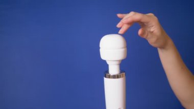 kadın el mavi bir arka plan üzerinde beyaz bir vibratör tutar. kopyalama alanı