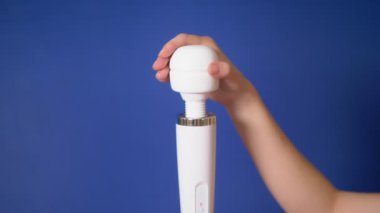kadın el mavi bir arka plan üzerinde beyaz bir vibratör tutar. kopyalama alanı