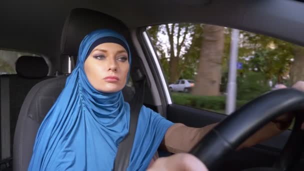 Krásná muslimka v modrém hidžábu, který řídil auto. jízdy během dne v ulicích města. — Stock video