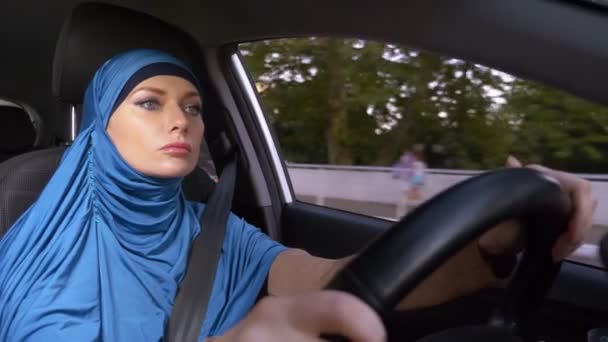 Krásná muslimka v modrém hidžábu, který řídil auto. jízdy během dne v ulicích města. — Stock video