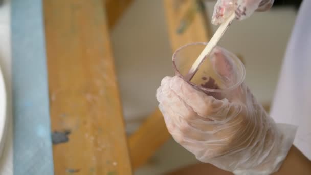 Yakın çekim, tek kullanımlık bir fincan boya karıştırma. sanatçılar işyeri. tuval üzerine akrilik boyalar ile çalışmak için iş akışının hazırlanması. sanat sıvısı — Stok video