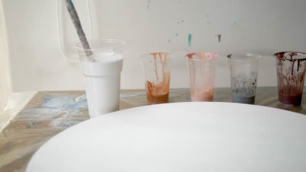 特写，将油漆混合在一次性杯子中。艺术家工作场所。准备用于画布上丙烯酸涂料的工作流程。艺术流体 — 图库视频影像