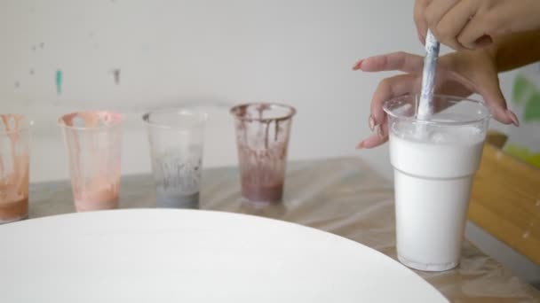 Primer plano, mezclando pintura en una taza desechable. artistas lugar de trabajo. preparación del flujo de trabajo para trabajar con pinturas acrílicas sobre lienzo. arte fluido — Vídeo de stock