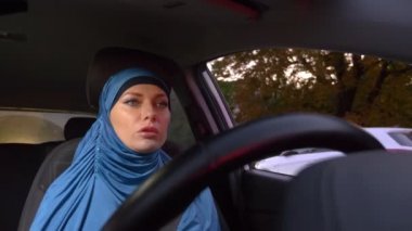 mavi hijab güzel müslüman kadın bir araba sürüş. şehrin sokaklarında gün boyunca sürmek.