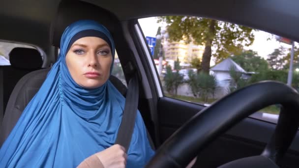 Mooie moslim vrouw in blauwe hijab rijden een auto. ritten overdag op de straten van de stad. — Stockvideo