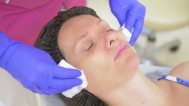 kozmetoloji kavramı. Yakın. Güzellik eltemizliği ve bir sünger ile bir kadın yüzüne dokunmak. Bir kadın yalan söylüyor ve dinleniyor..