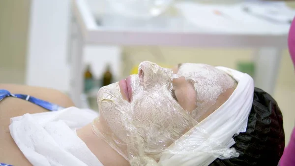 The concept of cosmetology. Close-up of a beautician applying a white mask with a brush on a womans face. — Stock Photo, Image