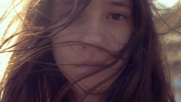 Tizenéves lány egy fehér ruhában, hosszú hajú néz elgondolkodva a tengerbe. szél alakul haj — Stock Fotó