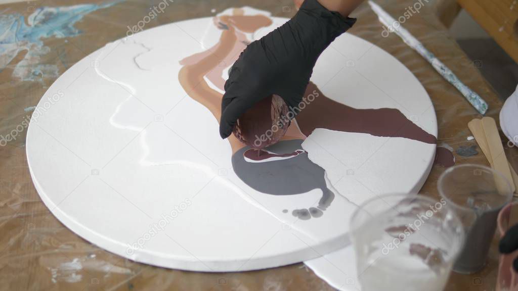 Workshop of liquid acrylics. Fluid art. female hands pouring acrylic paint on canvas. Creative work