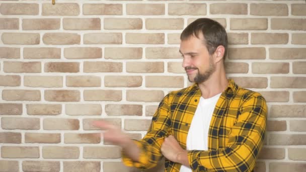 Handsome young man in a yellow checkered shirt, pointing to a place for text, a place for advertising — Stock Video