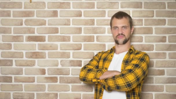 Handsome young man in a yellow checkered shirt, pointing to a place for text, a place for advertising — Stock Video