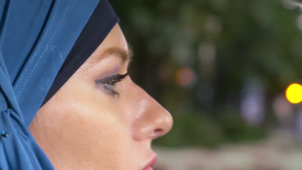 Schöne muslimische Frau im blauen Hidschab am Steuer eines Autos. Fahrgeschäfte tagsüber auf den Straßen der Stadt. — Stockvideo