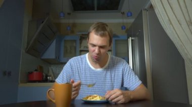 diyet konsepti, tatsız gıda. Sinirli ve rahatsız adam bir tabaktan yemek yemek ve hayal kırıklığına