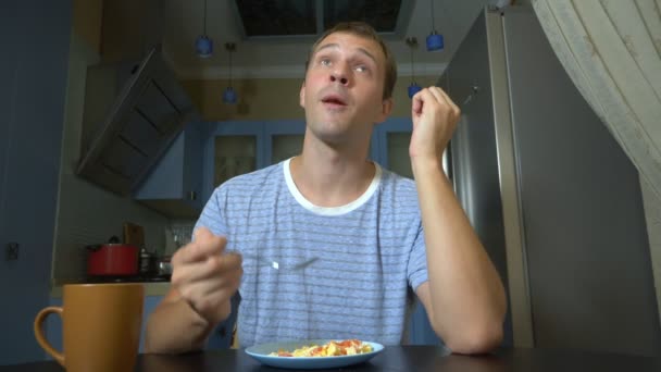 Homem sonhador comer comida sentado na cozinha em casa — Vídeo de Stock